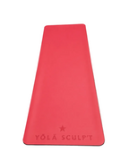 A bright pink yoga mat with embossed branding, laid flat on a textured gray concrete floor.