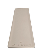 A light beige yoga mat with rounded corners and the embossed brand name 'YŌLĀ SCULPT' with a star logo, laid flat on a textured gray concrete surface.