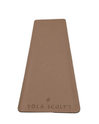 A rectangular tan yoga mat with rounded corners, featuring the embossed brand name 'YŌLĀ SCULPT' and a star logo near the bottom, laid flat on a textured gray concrete floor.