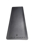 A black silicone yoga mat with the brand name 'YŌLÃ SCULP'T' and a star logo printed at the bottom, displayed on a textured gray concrete floor.