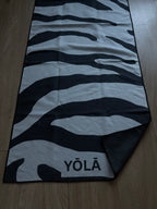 YŌLĀ SCULP'T Zebra Grip Towel featuring a black and white zebra print, made from premium microfiber suede with a non-slip silicone dot backing for hot Pilates and yoga.