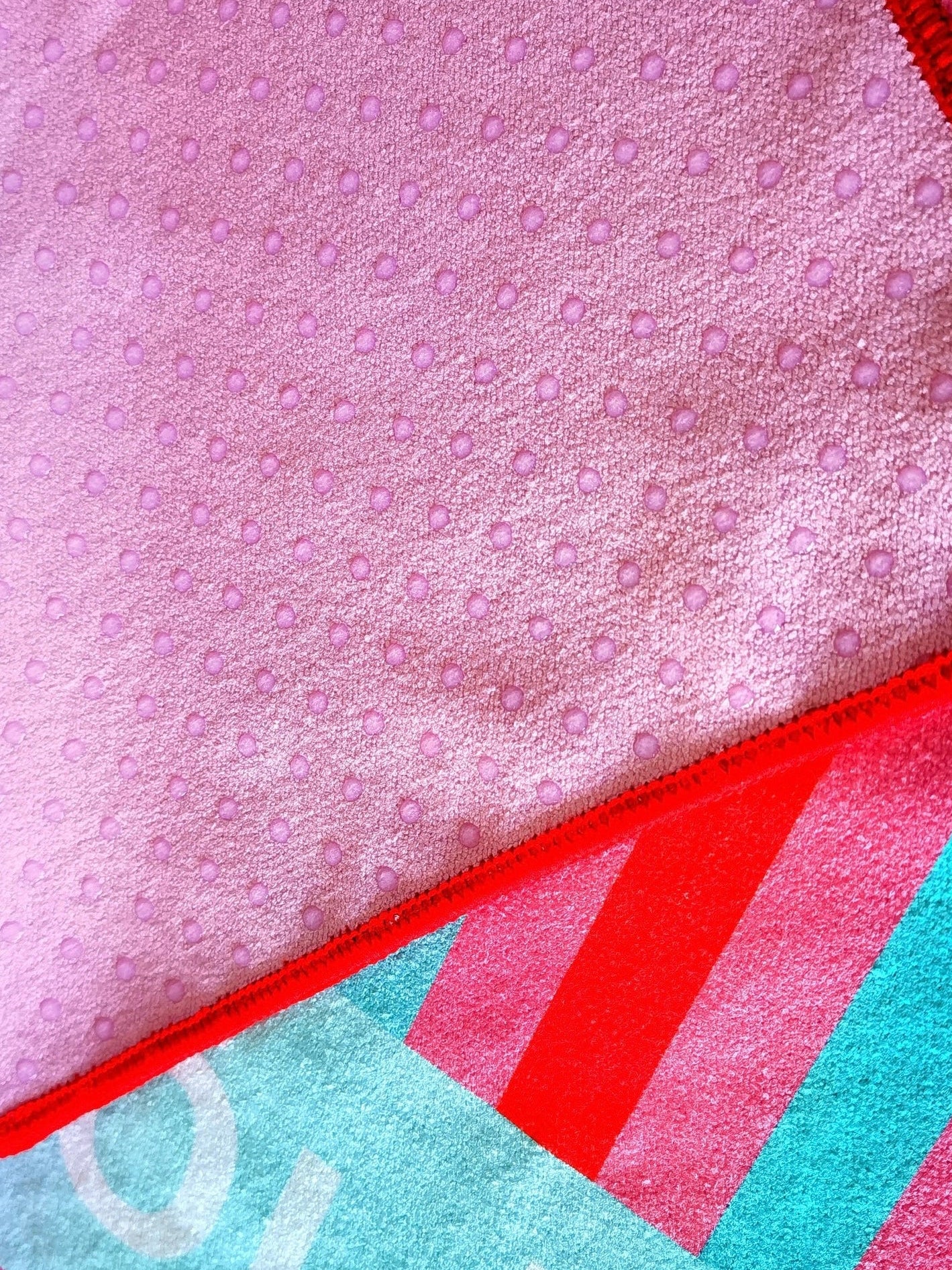 Close-up of Miami stripes yoga mat towel showing microfiber surface and non-slip silicone grip backing with stitched edge detail by Yola