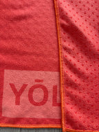Close-up of the YŌLĀ SCULP'T So Hot Grip Towel in orange featuring a premium microfiber suede surface and non-slip silicone dot backing for hot Pilates and yoga.